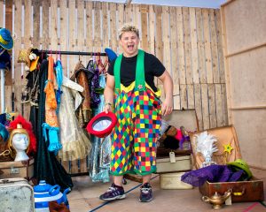 Josh Benson in colourful panto costumes smiling at the camera