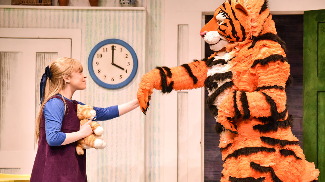 A fluffy tiger (right) holding a hand out that is held by a little girl.