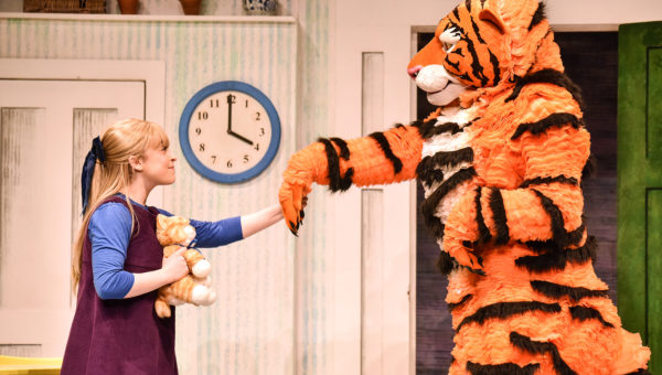 A fluffy tiger (right) holding a hand out that is held by a little girl.